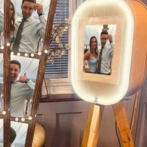 Photo booth hire for any occasion A couple posing together in front of a vintage pod photobooth with lights.