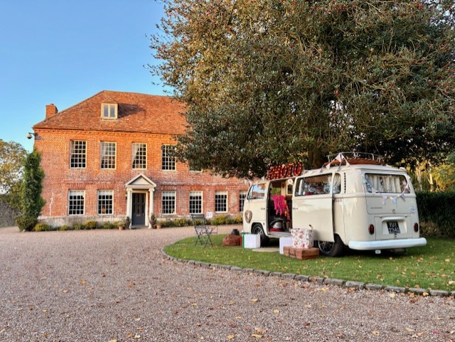Campervan photobooth at The Castle Westernhanger Vintage white van parked beside a large red-brick house in a garden setting.
