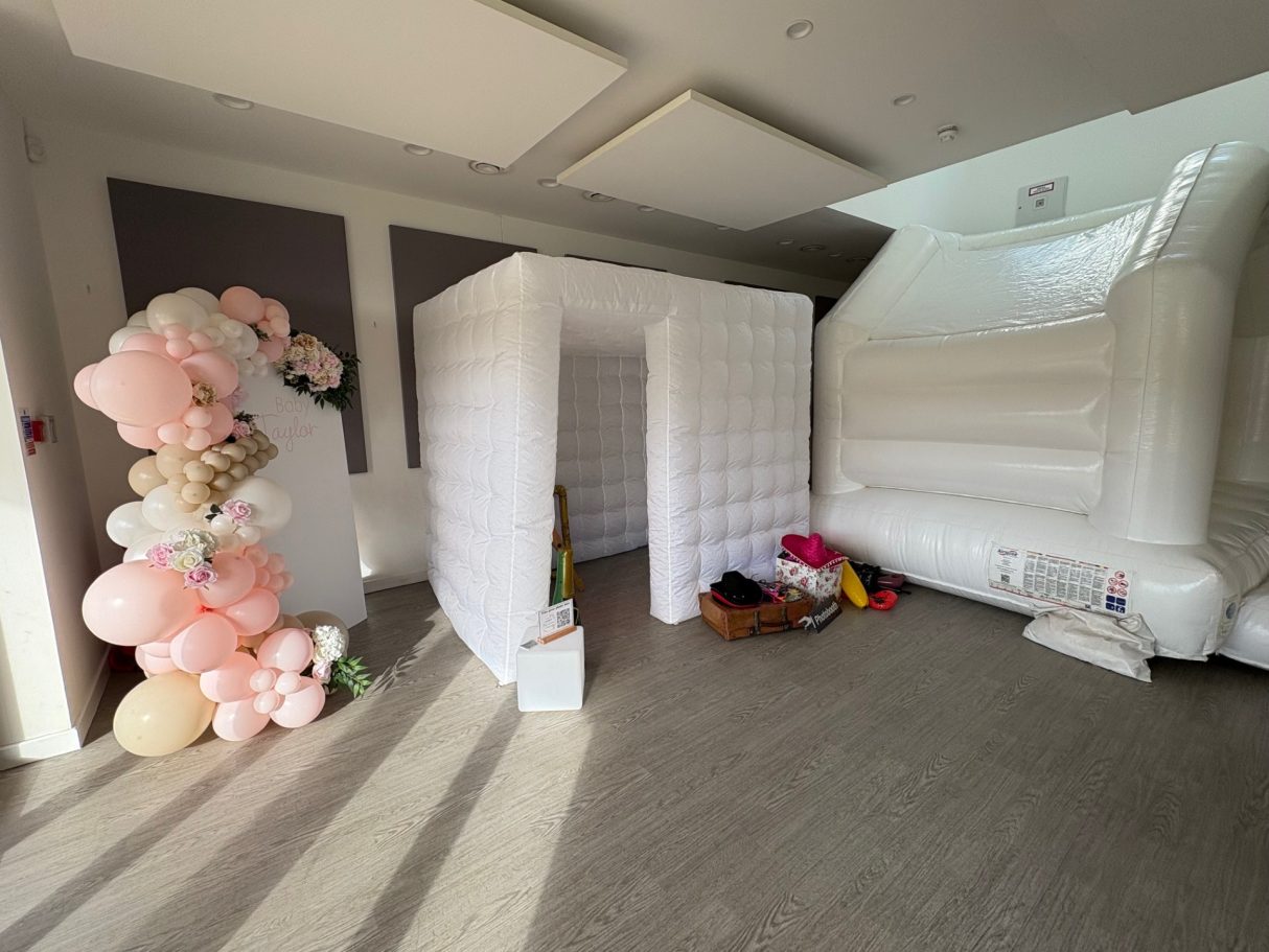 Professional photobooth enclosure A decorated indoor space with balloons, a photo booth, and a large inflatable structure.